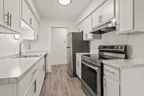 A kitchen with white cabinets and a marble countertop.